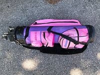 Pink nylon golf bag with black trims and multiple pockets, holding set of golf clubs internally.