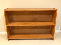 Front view of handmade solid wood bookcase showing two shelves and wood grain finish.