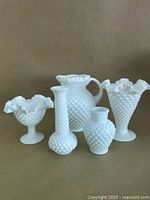 Lot of five white hobnail milk glass decorative pieces including vases and jug, all with textured hobnail surfaces and ruffled edges on some pieces.