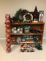 Wide view of the shelf filled with large and medium Christmas ornaments, wreaths, string lights, the nutcracker figure, and the large tin star on top.