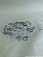 Image showing an assortment of silver and sterling silver jewellery on a plain background including rings, bangles, chains, and pendants.
