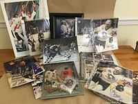 Photo of various autographed hockey photos, prints, and books laid out, showing signed images of players in action and framed memorabilia.