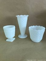 Photo of three vintage milk glass items, showing different shapes and textures including hobnail and ribbed designs