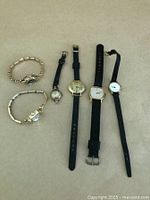 Photo of six assorted vintage ladies watches showing various designs and strap types, laid out flat with ruler for scale