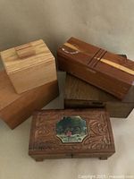 Group of six assorted vintage wooden boxes, showing different shapes, sizes, and decorative elements including carving and inlaid scenes.