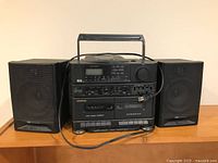 Front view of Samsung boom box stereo system with speakers on either side placed on wooden surface.