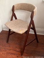 Side view of mid-century modern teak wood A-frame chair with beige tweed upholstery, showing worn fabric and wood condition.