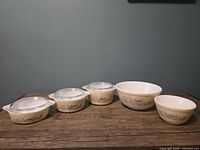 Full view of all eight pieces including three covered casseroles and two mixing bowls, all with Forest Fancies pattern.