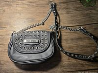 Full front view of black leather purse showing metal grommet flap and Harley Davidson nameplate.