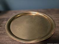 Top view of the round brass serving tray showing its flat surface and raised rim.