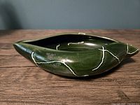 Side view of vintage green ceramic planter showing asymmetrical leaf shape and white crazing lines