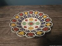 Top view of brass dish showing colorful enamel floral pattern and carved details.