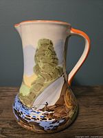 Front side of the jug showing waterfall, cliffs, and part of the river scene with brown rocks and greenery