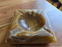 Angled close-up view showing the polished onyx surface and veining patterns on the ashtray, highlighting the smooth concave recess for ashes.