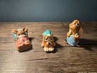 Three Pendelfin figurines including one dog and two bunnies on wood surface with blue background