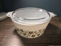 Front angle of Pyrex casserole dish with clear glass lid showing floral pattern and handles.