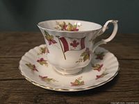 Teacup and saucer front view showing Canadian flag and maple leaf design, gold trim