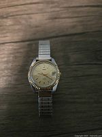 Front view of the vintage Timex ladies watch showing the cream dial, gold bezel, and stretch metal band.