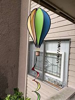 Photo showing colorful hot air balloon hanging spinner outdoors with spiral tail detail.