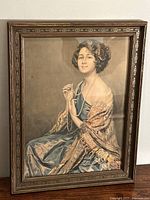 Front view of framed portrait print by Arthur C. Garratt showing young woman in blue dress holding pearls.