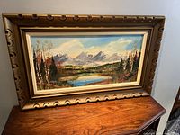 Framed oil painting titled "Golden Ears" depicting mountain scene with water and trees, wooden frame with decorative carvings
