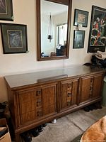 Front and angled views of the large wooden dresser showing nine drawers with metal handles and detailed paneled fronts.