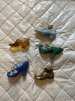 Overview of six miniature shoes on a quilted white background showing different colors and materials
