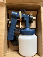 HVLP spray gun with white paint container inside a cardboard box