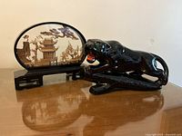 Side-by-side image showing the black porcelain stalking panther and the vintage hand carved cork diorama with pagoda