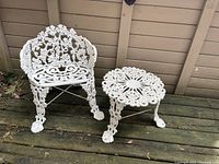 Full view of white powder coated cast aluminum patio chair and side table on wood deck with grapevine and leaf pattern