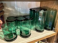 6 tall and 8 short green vintage glassware pieces arranged on a shelf, showing hexagonal or faceted green glass design.