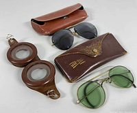 Photo showing the two pairs of sunglasses and the vintage leather goggles along with their cases