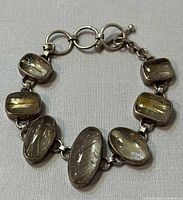 Close-up showing some of the cabochon-cut gemstones on the bracelet, highlighting the needle-like inclusions inside the stones.