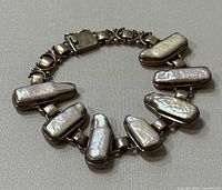 Top side view of the sterling silver bracelet with mother of pearl insets showing the arrangement and condition.