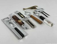 Full view of eight vintage bottle openers displayed on a white surface showing diverse shapes and handle materials including metal, wood, and decorative clear resin with embedded natural objects.