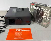 Photo showing the GAF slide projector from a side angle, instruction booklet, and original boxed Sawyer's Rotary Tray 100 carousel.