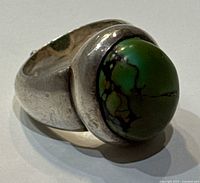Close-up photo of green turquoise stone set in a thick solid silver ring band.