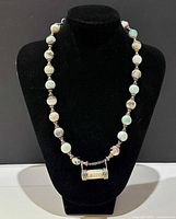 Full view of the 18-inch hand carved stone necklace displayed on black bust showing the bead arrangement and pendant.