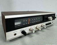 Full front-angle view of Lafayette LR-100 solid state receiver showing tuning dial, control knobs, input selector, tape out jack, and wood grain casing.