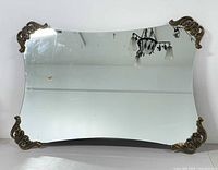 Full front view of large rectangular curved mirror with brass decorative corners showing overall shape and design.