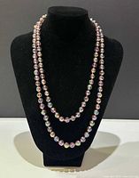 Necklace displayed on neck form showing length and bead details.