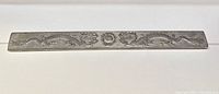 Full view of the rectangular silver bar with dragon and sun engravings, showing length and design.