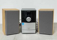 Front view of Sony CMT-EH10 micro hi-fi system main unit between two bookshelf speakers, showing condition and features