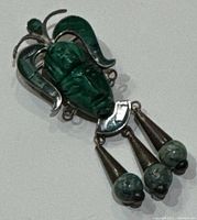 Close view of the carved jade face with silver headdress and dangling teardrops with jade beads.