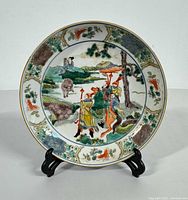 Front view of the bowl showing hand painted scene with figures, trees, and floral border