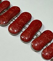 Close-up of elongated polished red coral stones with natural veining set in silver bezels.
