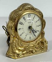 Front side angle view showing clock face, intricate Western motif including cowboy boots and hat with a gold-tone frame.