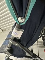 Close-up of stroller fabric showing navy and teal colors and part of frame with a label '106'