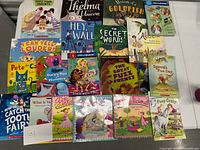 Top-down view of all 23 children's books showing colorful covers and titles arranged in rows on a flat surface.