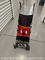 Front view of Disney Baby umbrella stroller showing Mickey Mouse themed seat fabric, handles, and front wheels.